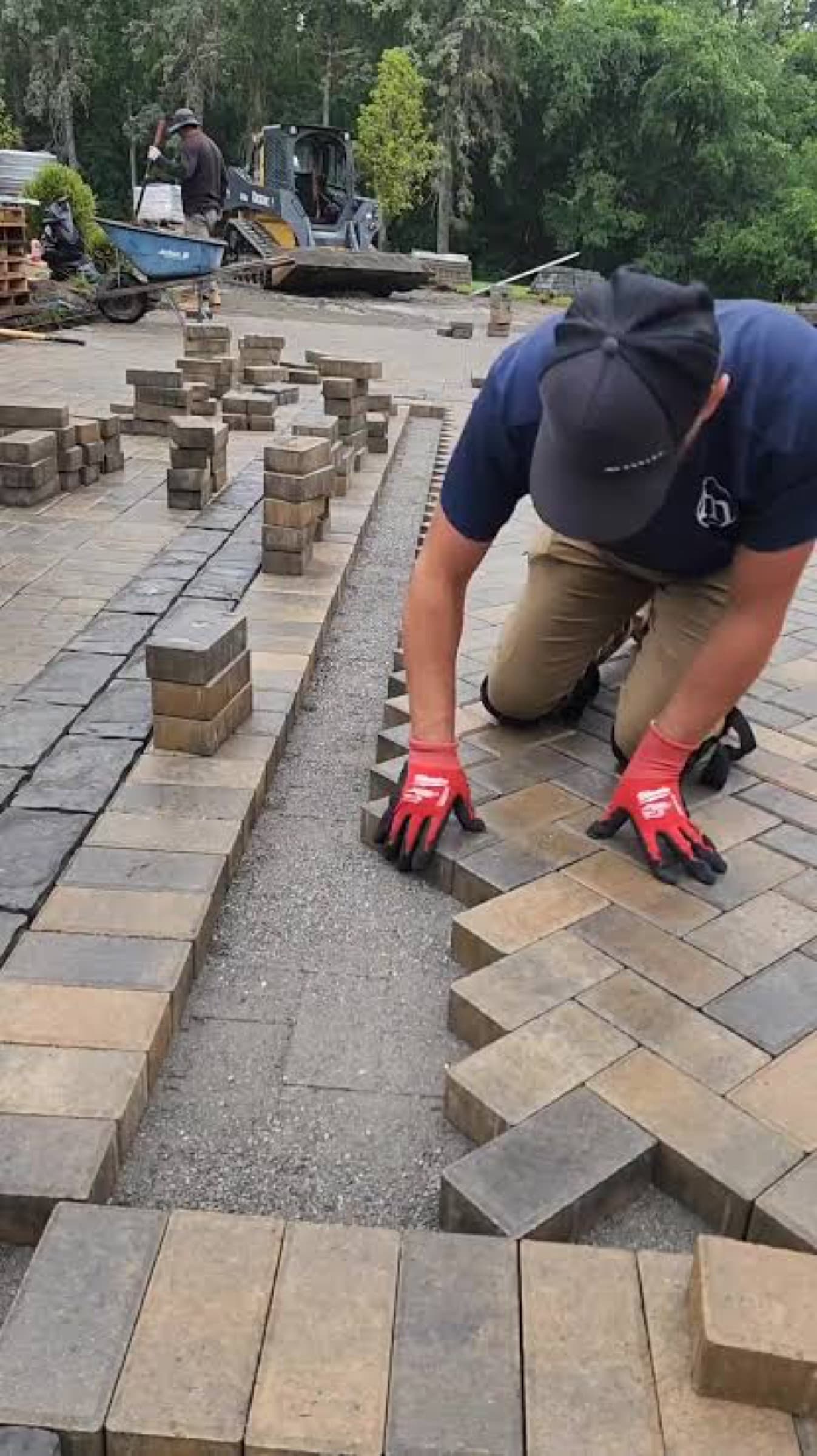 FCL crew member kneeling to set pavers by hand along a string line