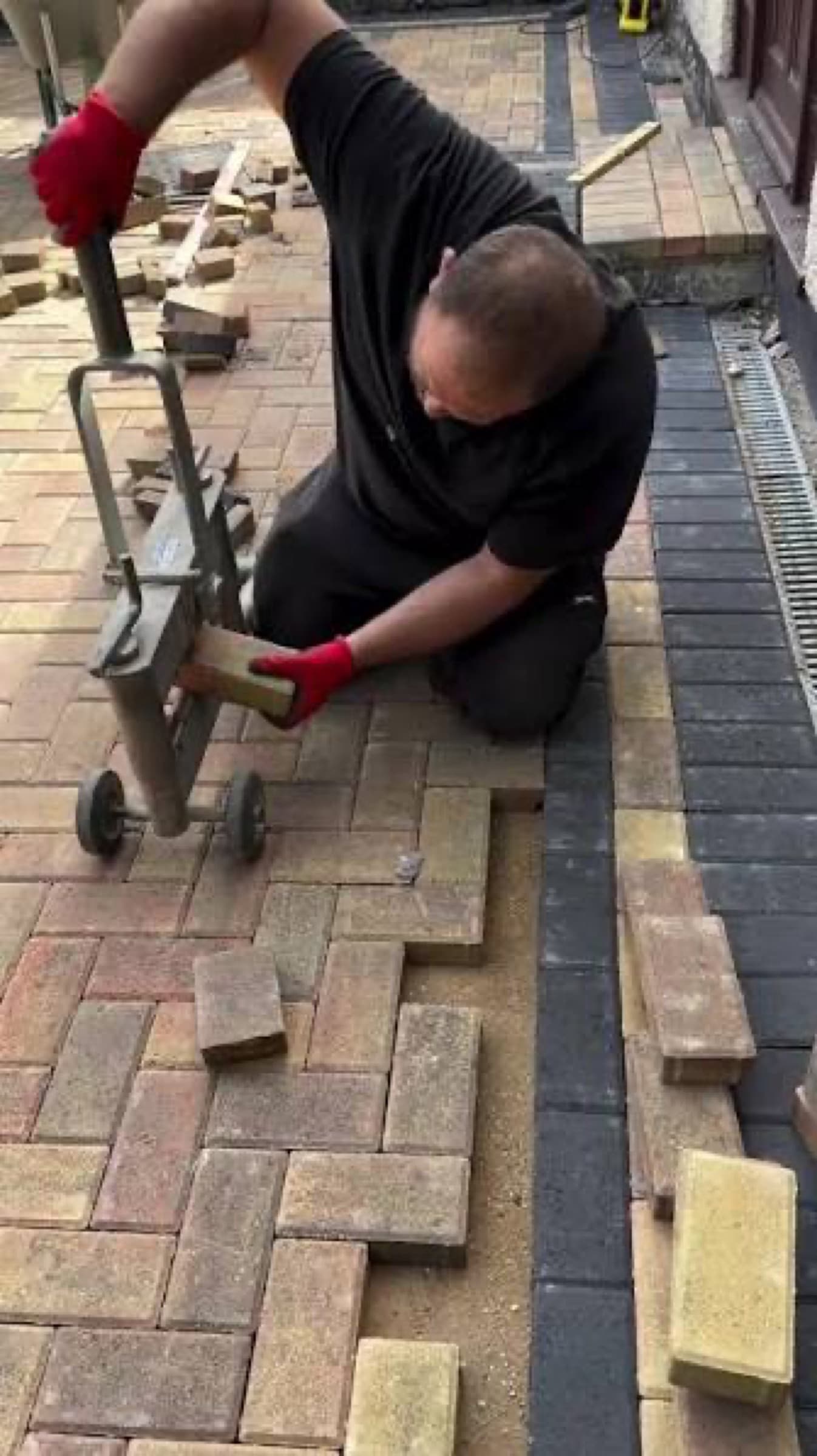Crew member cutting a paver to size with a block splitter on site