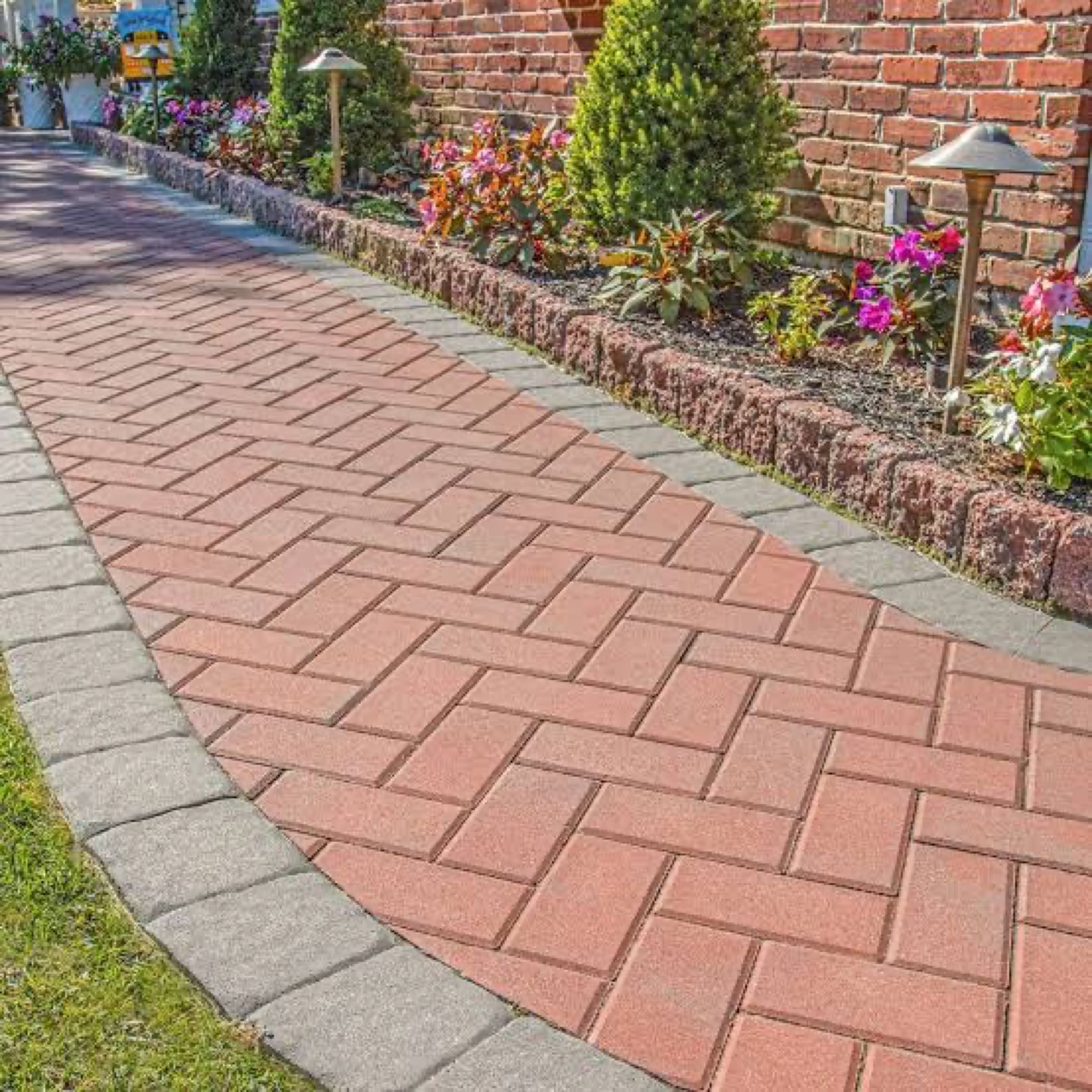 Red brick paver walkway in a running bond with a grey soldier-course border, planted bed alongside
