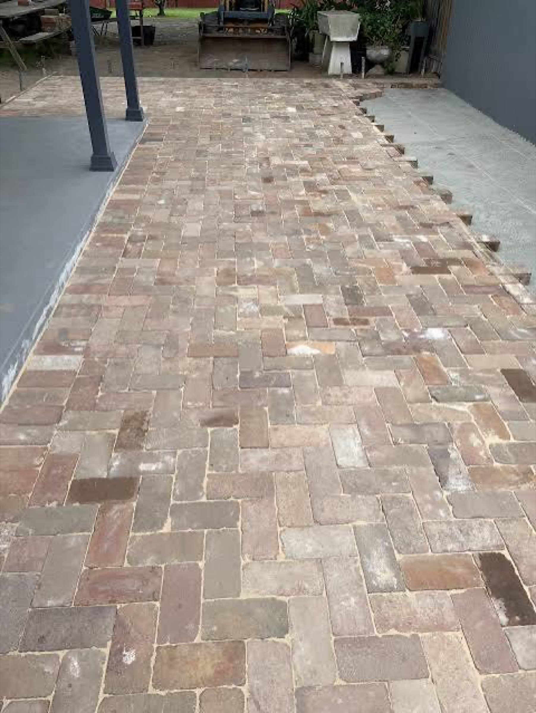 Reclaimed brick patio part-laid in a herringbone pattern beside a covered porch