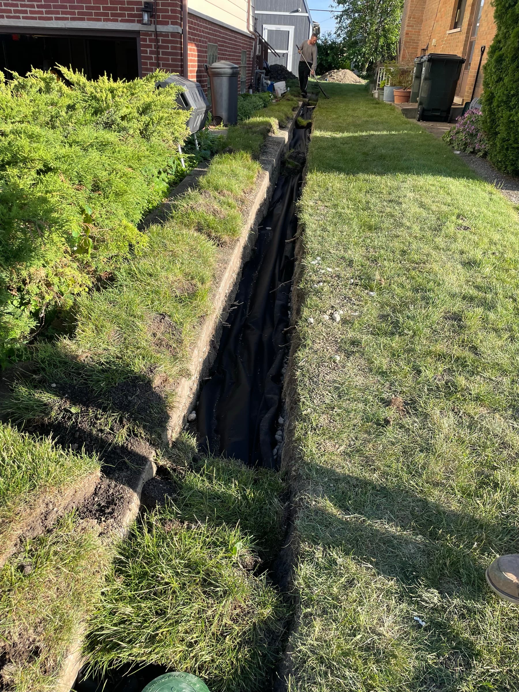 Deep drainage trench running the length of a side yard between house and lawn