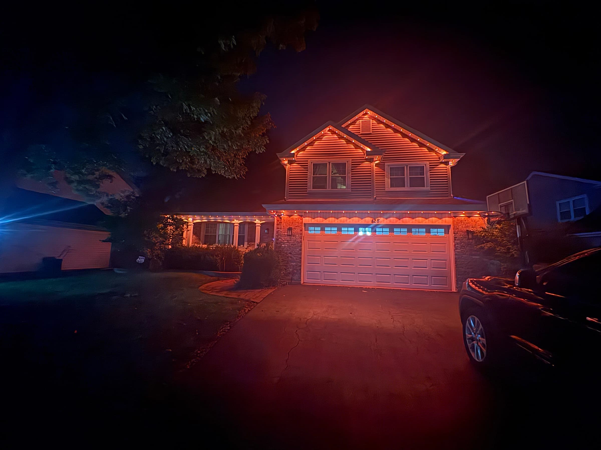 The same permanent system set to warm amber, lighting the roofline on an ordinary evening