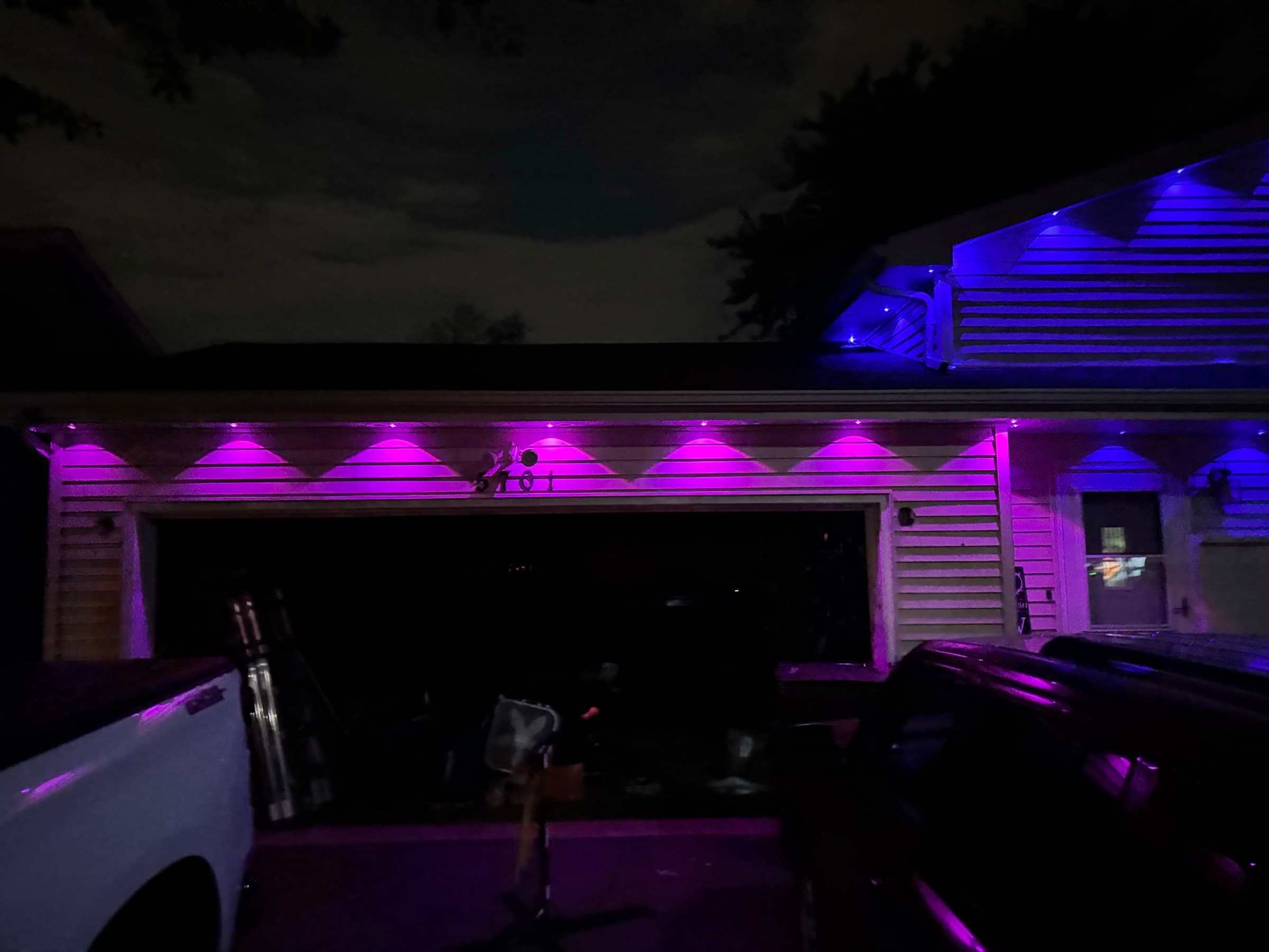 The same permanent fixtures set to purple over the garage and blue across the upper gable, showing the colour-change capability