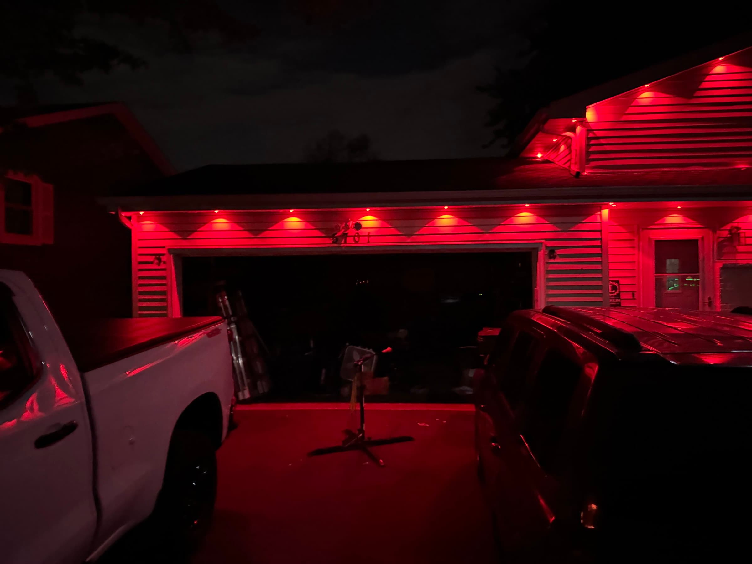 The full front of a house lit in red by its permanent roofline system