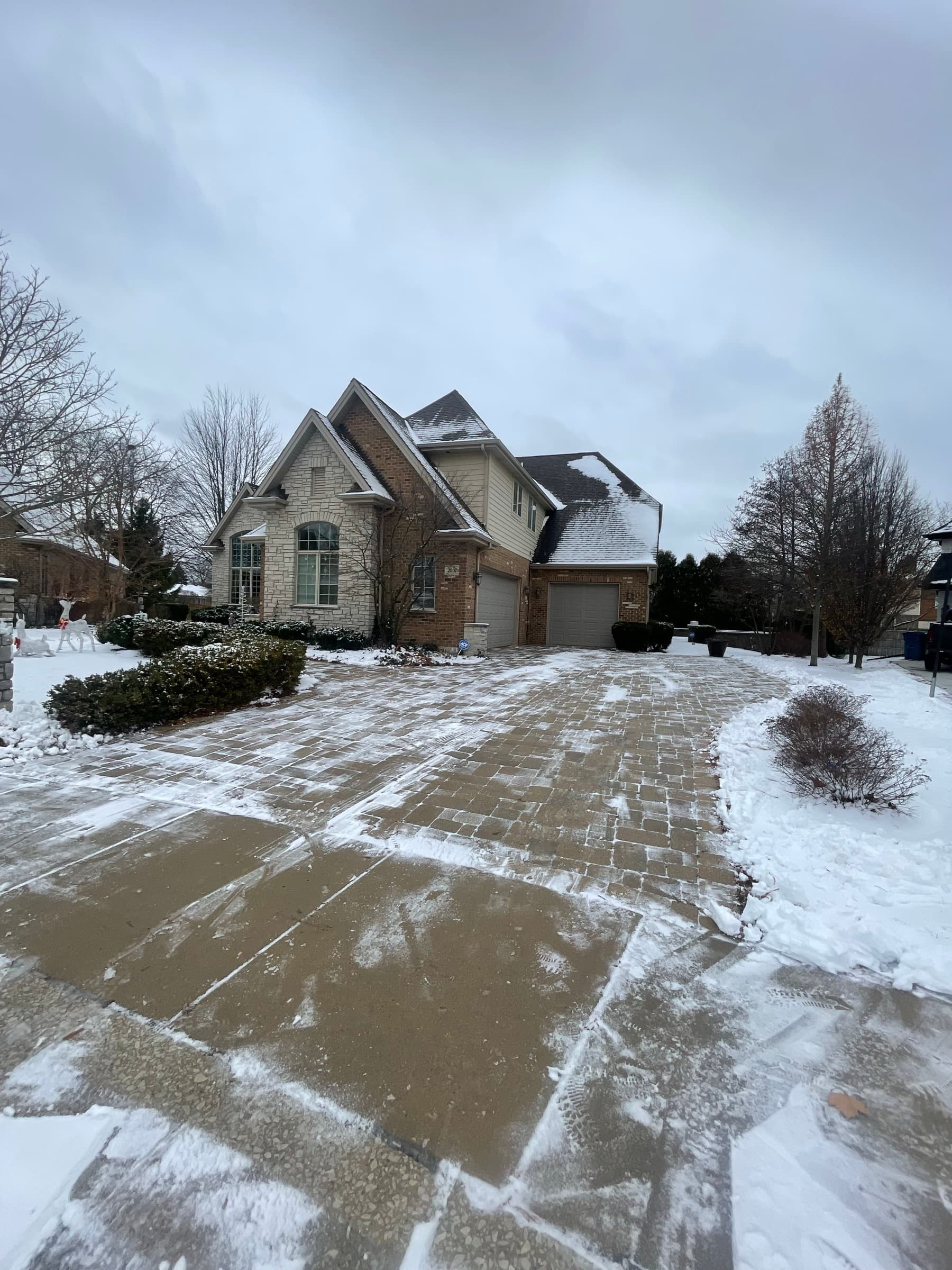 Wide driveway cleared down to the surface after a snowfall, snow still lying on the lawn either side