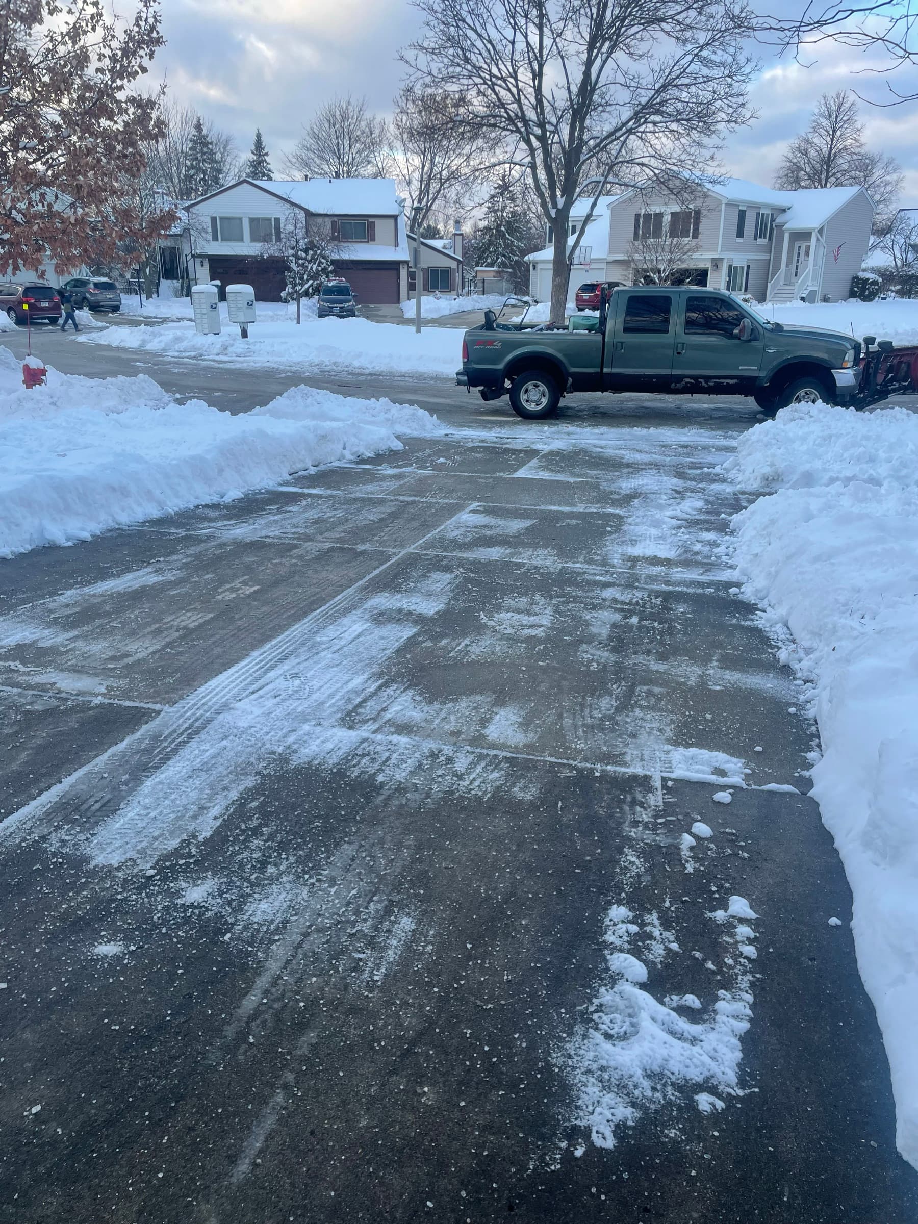 Plowed driveway and street with high snow banks and the FCL truck parked alongside